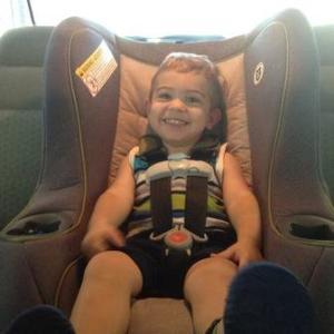 Smiling toddler buckled into a properly-installed car seat