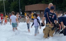 Children and firefighters playing in foam