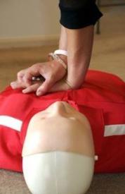 Hands performing chest compressions on CPR dummy